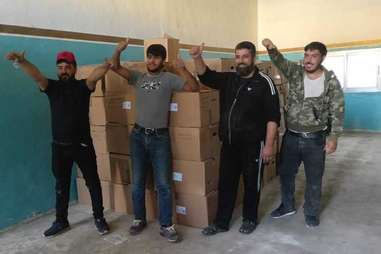 Volunteers standing next to rows of boxes posing for a photo