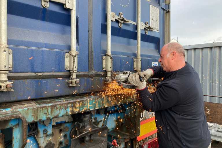 A person using a circular saw to remove the locks on a container