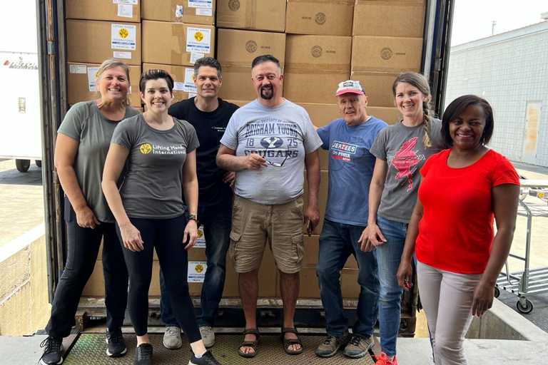 Volunteers standing next to a truck they have filled to full capacity with boxes of donated items, posing for a photo